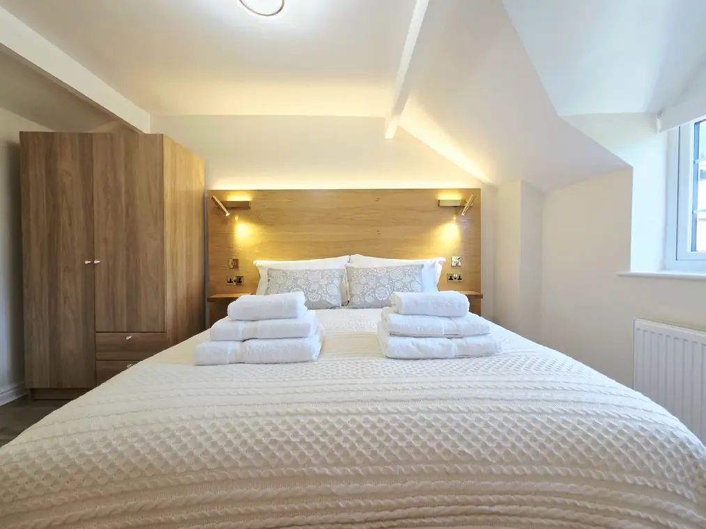 The kingsize bed head-on with its oak-veneered headboard and brass reading lights
