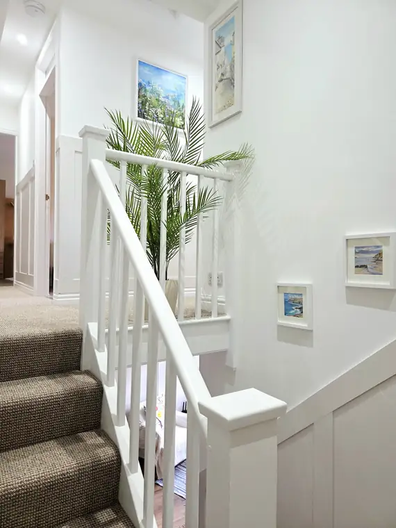 The staircase with its gallery of framed coastal prints