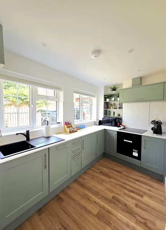 The sage-green Shaker kitchen units and sink