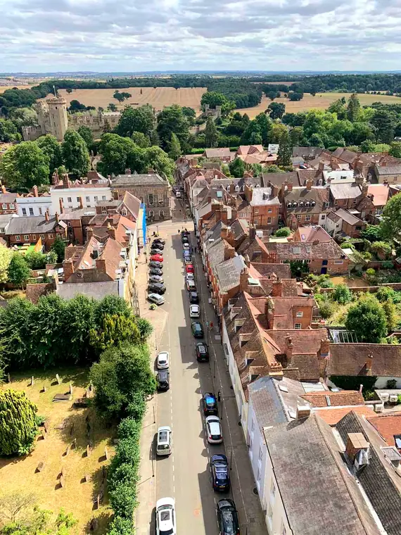 Looking down from St Mary's church tower along Church Street and then Castle Street towards Warwick Castle, with its great tower among trees to the left and open countryside beyond